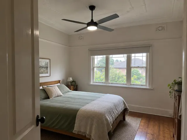 Ceiling fan in a white bedroom with window and timber floor in Ourimbah