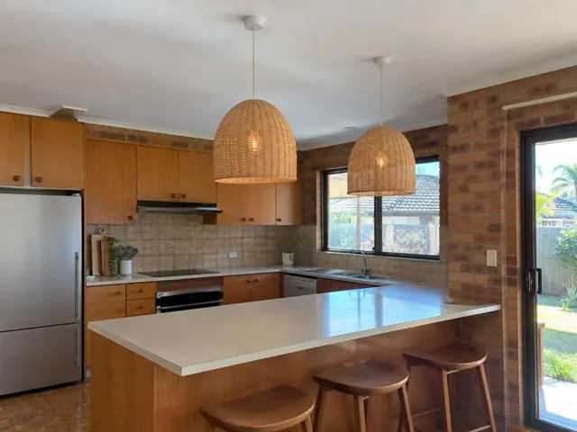 Two woven pendant lights over a kitchen island in a brick-walled home kitchen in Tuggerah